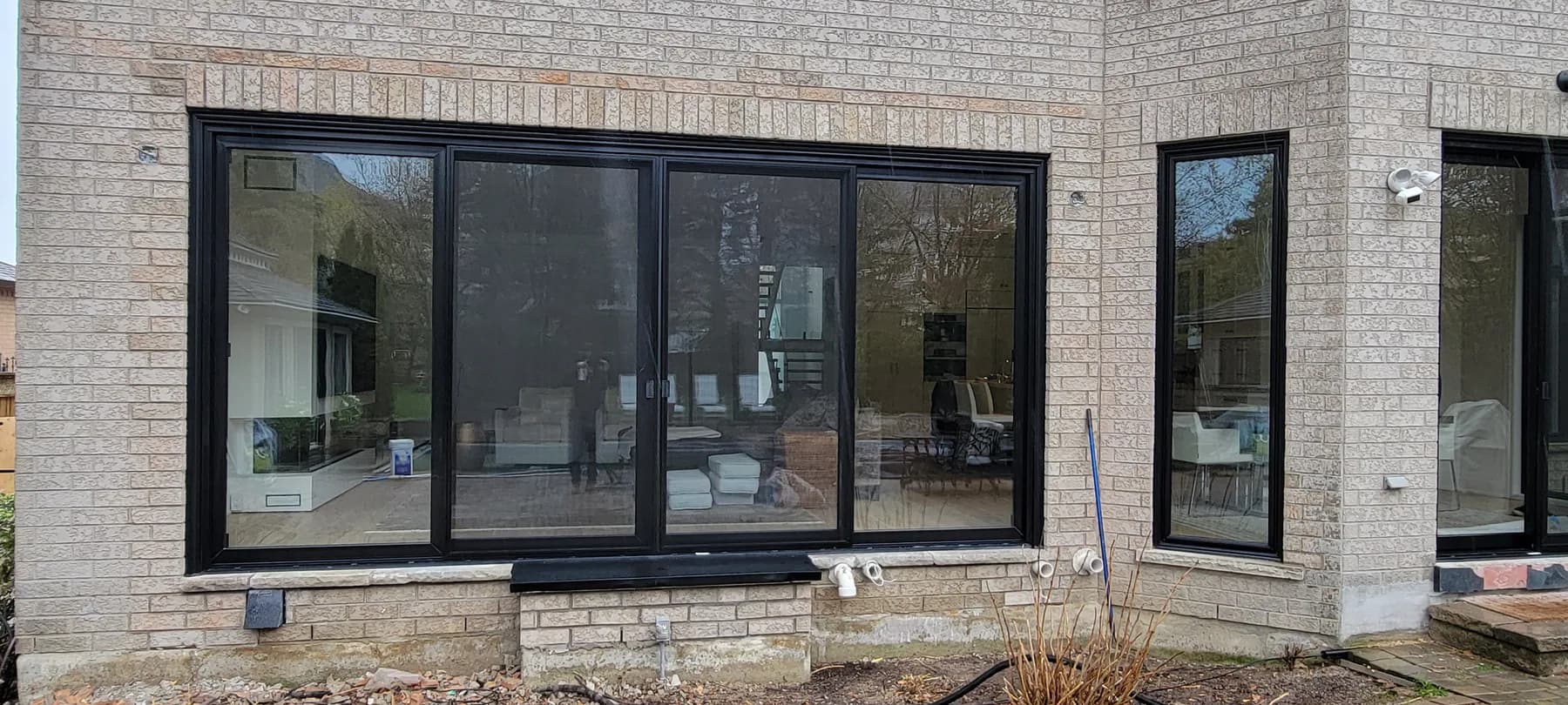 Wide black multi-panel sliding door installed by Better View on a brick home