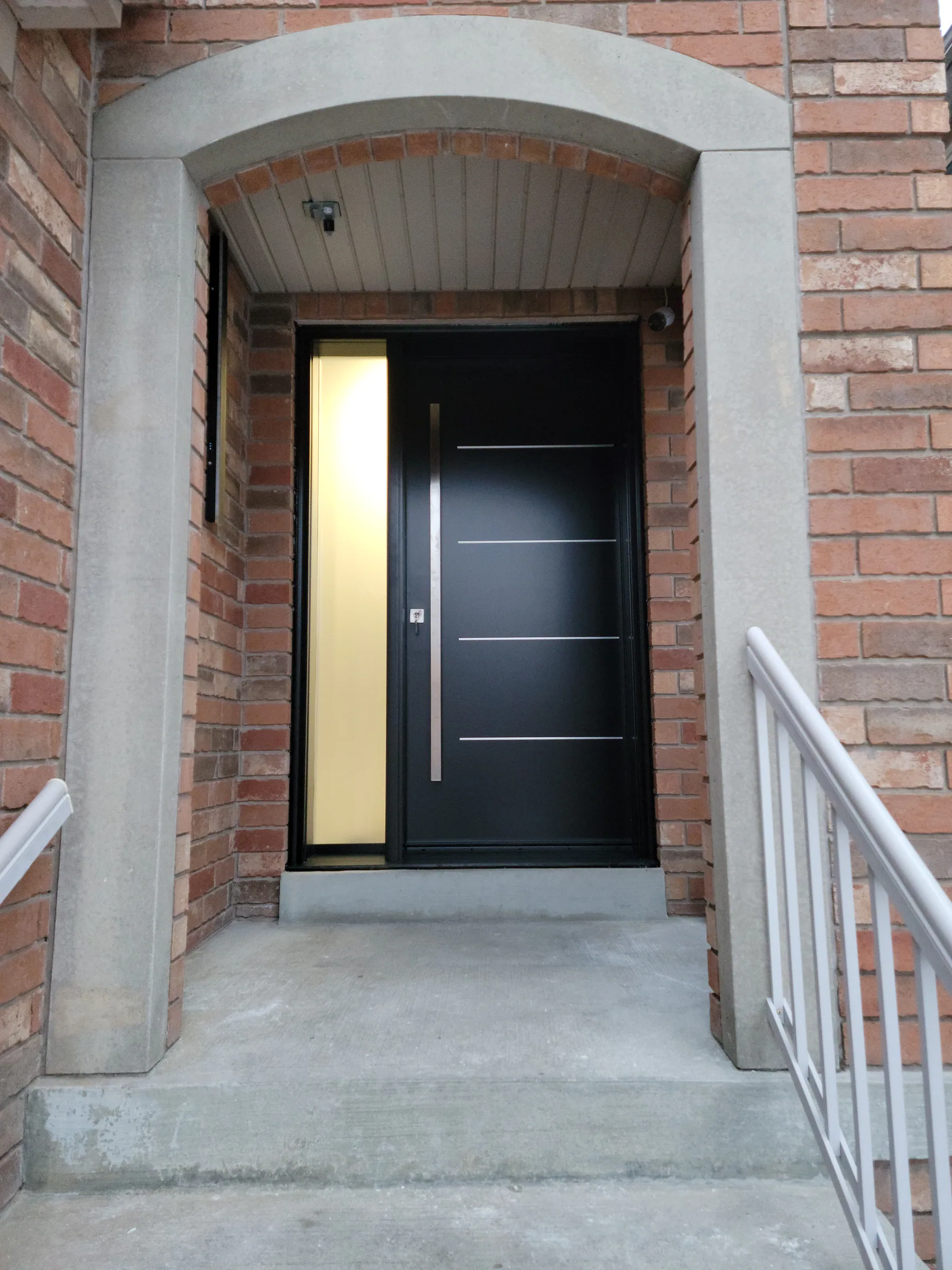 Modern steel entry door with a glass strip and long pull handle installed by Better View
