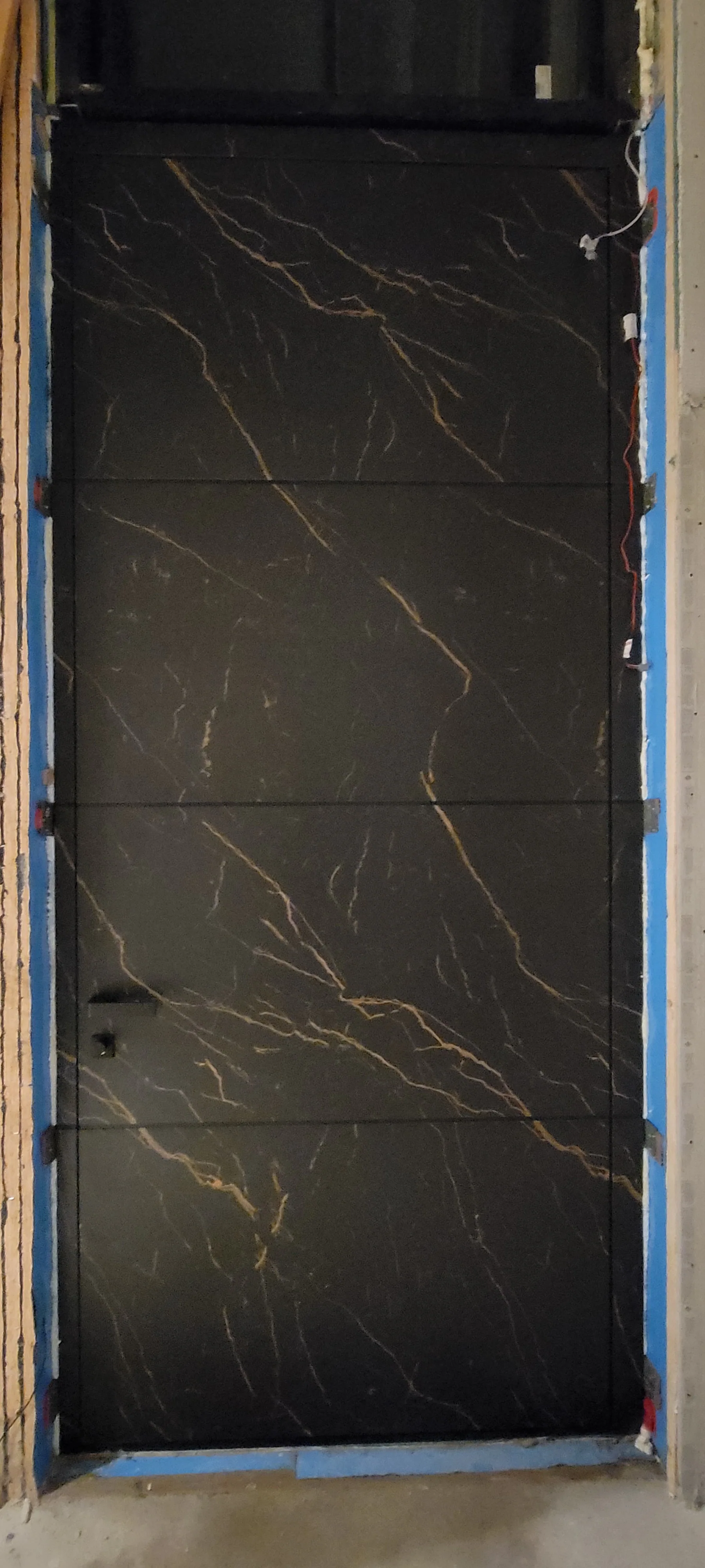 Oversized marble-look pivot door during installation