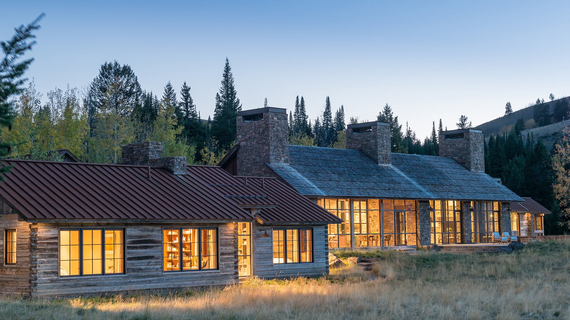 Warm home exterior with large windows at dusk