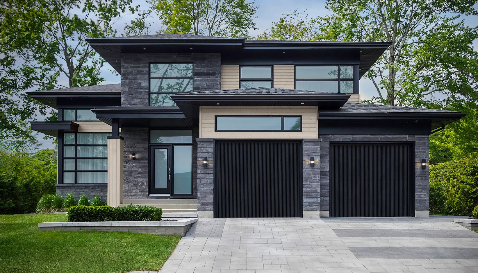 Two black vertical slat garage doors on a modern stone house