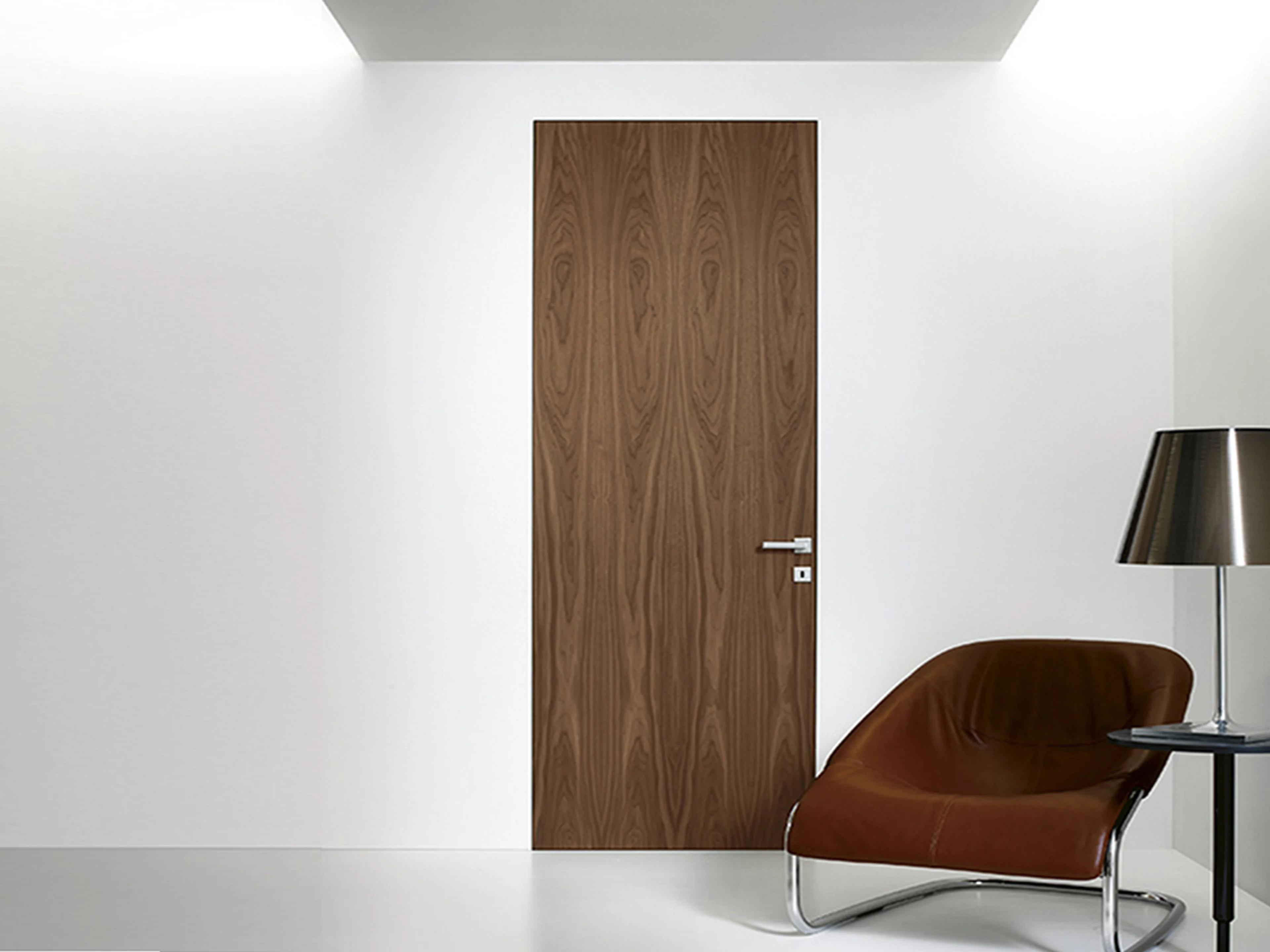 Walnut frameless interior door flush with a white wall