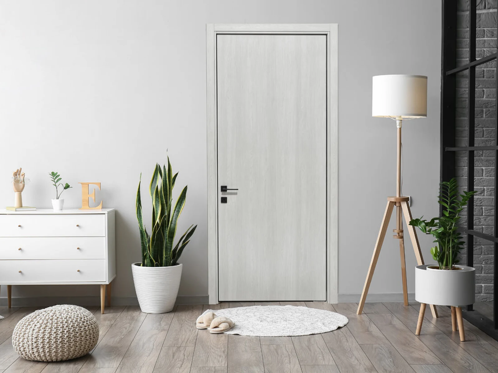 Light wood interior door with modern black hardware in a bright room